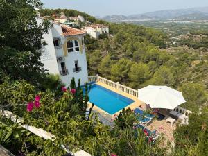 a villa with a swimming pool and an umbrella at Villa Arturo Tossal Gross in La Font D´En Carròs
