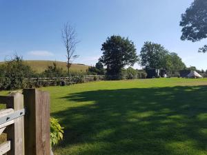 a large field with a fence and a large shadow at Merrywell Shepherds Hut & Paddock in Offenham +15 photos