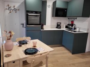 Metz vieille ville quartier Sainte Croix "La Colline" في ميتز: مطبخ مع دواليب خضراء وطاولة عليها صحن +18 صورة