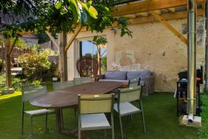 a wooden table and chairs in a yard at Au calme in Houssay