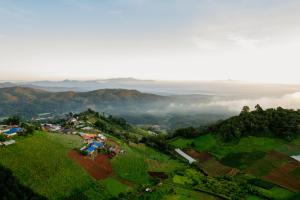 an aerial view of a village on a hill with clouds in the background at บ้านละอองฟ้า1 แอร์ ม่อนแจ่ม วิวดอยหลวงเชียงดาว in Mon Jam