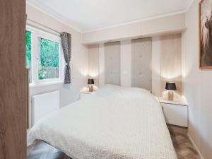 a bedroom with a white bed and two lamps at chalet in the woods with pool in Vledder