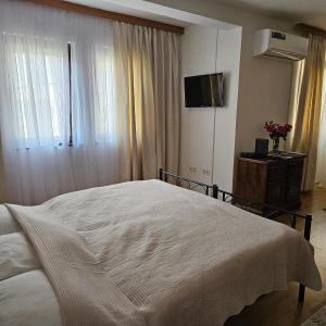 a bedroom with a white bed and a television at AC House Apartments in Sarajevo +30 photos