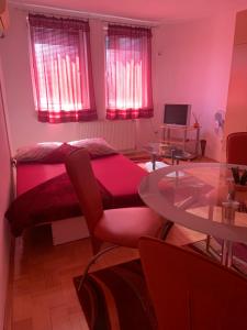 a room with a bed and a table and windows at Urban Hideout City Center Nis in Niš