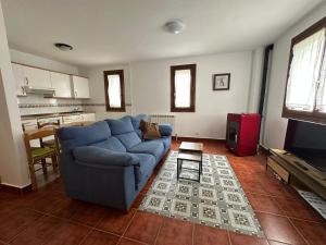 a living room with a blue couch and a kitchen at Retaetxe in Orbaiceta +8 photos