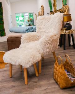 a white furry chair with wooden legs in a living room at Waldzauber Appartement in Horhausen