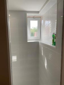 a bathroom with white tiles and a window at Joli appartement au calme in Bruay-la-Buissiere