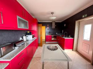 una cocina con armarios rojos y una mesa. en Cerca do casal, en Santo Tirso 44 fotos más