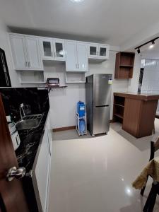 a kitchen with white cabinets and a stainless steel refrigerator at Casa Alegre Lipa in Lipa +9 photos