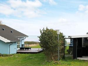 a house with a bench on a deck with the ocean in the background at 6 person holiday home in Hadsund-By Traum in Hadsund