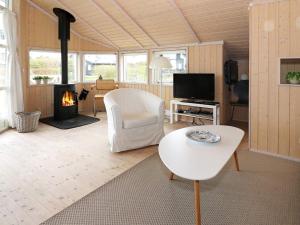 a living room with a white chair and a fireplace at 6 person holiday home in Hadsund-By Traum in Hadsund