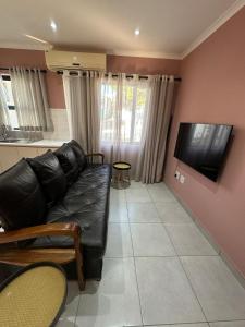 温特和克Little Haven Conerstone cottage的客厅里有一张黑色皮沙发和一台平板电视