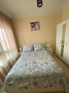 a bedroom with a bed with a blue and white comforter at Joli appartement balnéaire avec piscine in Tangier +37 photos