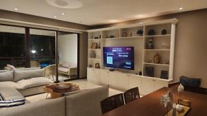 a living room with a couch and a television at Hermoso departamento Acapulco in Acapulco
