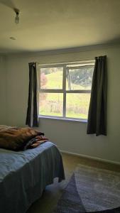 a bedroom with a bed and a large window at Te Anga Farmstay in Te Kuiti