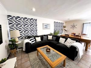 a living room with a black couch and a table at The Cinnamons in Plettenberg Bay