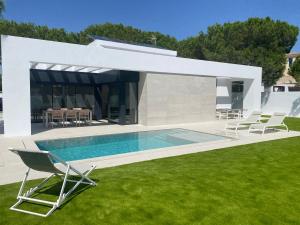 a swimming pool in a backyard with chairs and a house at Esmeralda Sea Villa - Beach&Golf Sancti Petri in Novo Sancti Petri