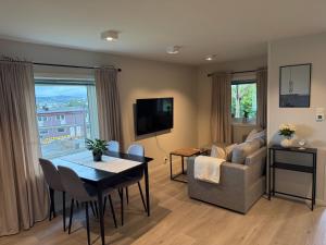 a living room with a table and a couch and a television at Sentral og koselig leilighet in Tromsø