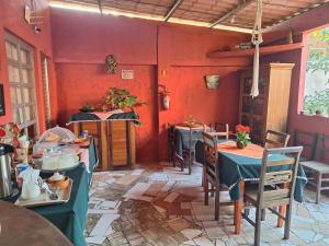 a restaurant with tables and chairs and red walls at Pousada Aconchego Recanto Do Mar - São Sebastião - Caraguatatuba in São Sebastião