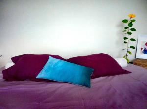 a bed with purple pillows and a vase with a flower at Ático encima del mar in Santa Cruz de la Palma