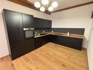 a kitchen with black cabinets and a wooden floor at Jenbachnest in Bad Feilnbach
