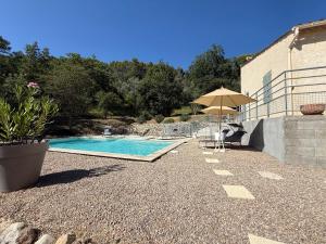 a swimming pool with an umbrella next to a building at Villa Lola in Bargemon