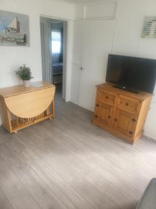a living room with a flat screen tv on a wooden cabinet at The Bobbers in Great Yarmouth +2 photos