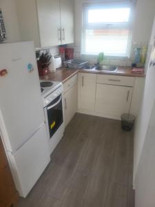 a kitchen with white appliances and a wooden floor at The Bobbers in Great Yarmouth