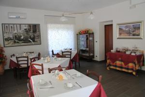 ヴィッラピアーナにあるB&B MeriGio'の白いテーブルと赤いテーブルクロスの椅子が備わるレストラン