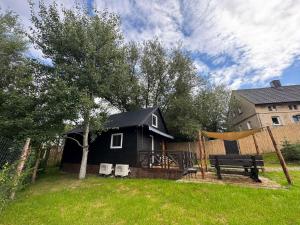 a black house with a playground and a swing at Wiedźmowa Chata in Leśna