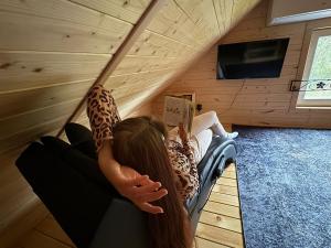 a girl laying on a hammock reading a book at Wiedźmowa Chata in Leśna