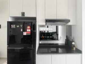 a kitchen with a black refrigerator and white cabinets at Seri Alam Cozy Studio by YHA in Masai
