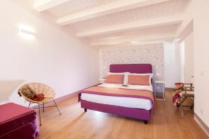 a bedroom with a purple bed and a chair at Radicata Tuscany Relais in Albinia