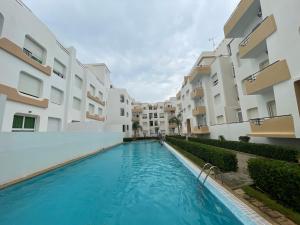 a swimming pool in front of some apartment buildings at Joli appartement balnéaire avec piscine in Tangier