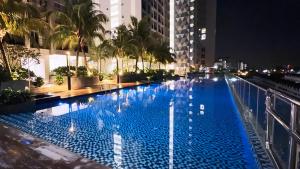 a large blue swimming pool in a city at night at Seri Alam Cozy Studio by YHA in Masai