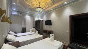 a hotel room with two beds and a tv at Al Amin Hotel in Khiva