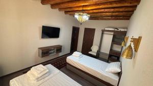 a room with two beds and a television in it at Al Amin Hotel in Khiva
