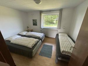 Dos camas en una habitación pequeña con ventana. en Fiskesøens Hus - Lige ud til vandet - Sø & Å, en Bylderup-Bov
