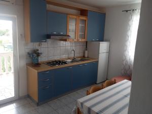 una cucina con armadi blu, lavandino e tavolo di Apartmani Ćućić a Lopar