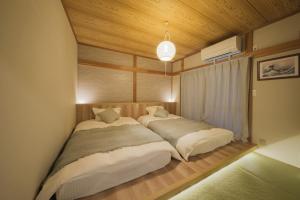 two beds in a room with wooden ceilings at Breeze Stay Shiohama in Tokyo