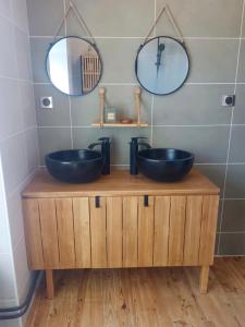 two sinks on a wooden stand in a bathroom with mirrors at La petite Maison in Vézézoux +9 photos