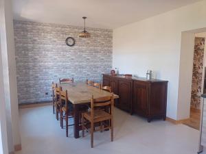 a dining room with a table and chairs and a brick wall at La petite Maison in Vézézoux