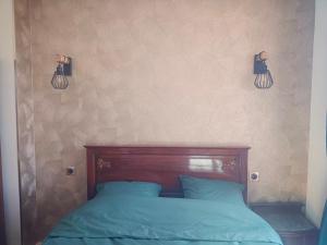 a bed with blue sheets and two lights on the wall at La petite Maison in Vézézoux