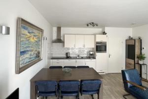 a kitchen with a wooden table and blue chairs at Sleedoornstraat 3 in Cadzand