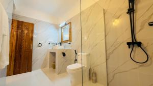 a bathroom with a toilet and a glass shower at Moya Beach Hotel in Marumbi +47 photos