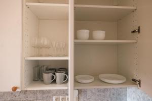 un garde-manger blanc avec de la vaisselle, des tasses et des assiettes dans l'établissement Nest 5B, à Bratislava 13 autres photos