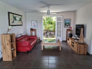 a living room with a red couch and a coffee table at Belle Villa 3 chambres piscine Rivière Salée in Rivière-Salée