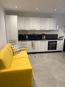 a living room with a yellow couch in a kitchen at Appartamento Pineta casa vacanze Sci & Natura in Varena