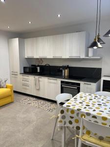 a kitchen with a table and white cabinets and a yellow chair at Appartamento Pineta casa vacanze Sci & Natura in Varena