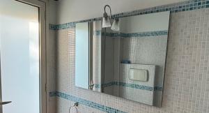 een spiegel in een badkamer met blauwe tegels op de muur bij Terrace Garden Apartment in Acitrezza +18 foto's